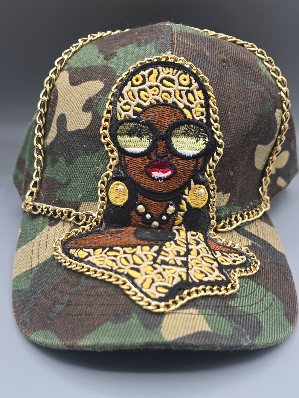 Camouflage Cap with African Woman Patch - Gold Chain Accent
